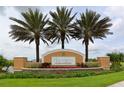 Welcoming entrance sign to Harmony at Lakewood Ranch with vibrant landscaping and palm trees at 5520 Coachwood Cv, Bradenton, FL 34211