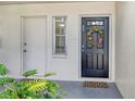 Charming front door entrance with a colorful wreath, welcome mat, and vibrant green plants at 7173 W Country Club N Dr # 141, Sarasota, FL 34243