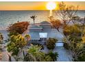 Striking aerial view of a beachfront property with mature trees, expansive roofline, and tranquil ocean vista at 8592 Hidden Lagoon Rd, Sarasota, FL 34242