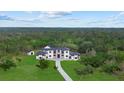 Aerial view of a modern home surrounded by lush greenery and a long driveway at 20307 74Th E Ave, Bradenton, FL 34202