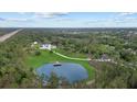 Aerial view of a modern home with a pond and a long driveway surrounded by lush greenery at 20307 74Th E Ave, Bradenton, FL 34202
