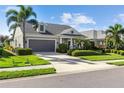 Beautiful single-story home showcasing a well-manicured lawn, a two-car garage, and mature palm trees at 6936 White Willow Ct, Sarasota, FL 34243