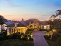 Stunning exterior home view featuring professional landscaping and a paver driveway, beautifully lit at dusk at 72 Grande Fairway, Englewood, FL 34223