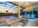 Relaxing outdoor patio with a tiki bar, fire table, and comfortable seating overlooking a sparkling pool at 72 Grande Fairway, Englewood, FL 34223