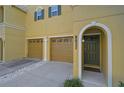 Close-up of a bright yellow townhouse featuring a two-car garage and an arched doorway at 8827 White Sage Loop, Lakewood Ranch, FL 34202