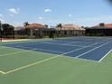 Outdoor tennis court with green and blue surface and shaded seating area near surrounding homes at 3724 71St E Ter, Sarasota, FL 34243