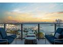Serene balcony view with outdoor seating overlooking a marina filled with boats, set against a colorful sunset backdrop at 1155 N Gulfstream Ave # 706, Sarasota, FL 34236