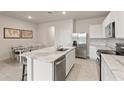 Modern kitchen with stainless steel appliances, white cabinetry, and an island with marble countertops at 17620 Crescent Moon Loop, Bradenton, FL 34211