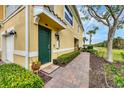 Inviting townhome entrance featuring a green front door, brick walkway, and lush green landscaping at 232 Explorer Dr # 15, Osprey, FL 34229
