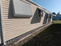 A close up side view of a beige mobile home with awning on a green lawn at 320 Tropic Dr, Osprey, FL 34229