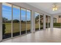 Enclosed sunroom with tile floors and expansive sliding glass doors providing panoramic views of the lush green backyard at 4044 Penshurst Park, Sarasota, FL 34235
