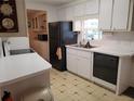 This is a kitchen with white cabinets, a black fridge, and an adjacent dining area at 5536 Denmark Dr, Bradenton, FL 34207