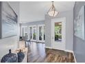 Bright foyer with wood floors, decor and light fixture leading to dining area with French doors at 5881 Girona Pl, Sarasota, FL 34238
