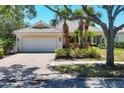 Inviting single-story home featuring a tile roof, brick driveway, and tropical landscaping at 5881 Girona Pl, Sarasota, FL 34238