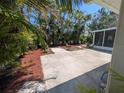 A charming backyard features a concrete patio surrounded by lush tropical landscaping and a screened-in lanai at 609 Glen Oak Rd, Venice, FL 34293