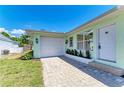 This home features a single-car garage and a paver driveway with mature landscaping at 148 N Blvd Of The Presidents, Sarasota, FL 34236