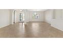 Bright living room with arched doorways, tile flooring, and large windows at 19798 Cobblestone Cir, Venice, FL 34292