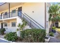 A side view of a condo building with stair access, complimented by lush shrubs and a verdant palm tree at 2300 Stickney Point Rd # 125, Sarasota, FL 34231