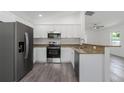 Modern kitchen featuring stainless steel appliances, granite countertops, and gray wood flooring at 3712 19Th E St, Bradenton, FL 34208
