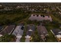Aerial view of a residential community with a pond, mature trees and screened pools at 5023 Brickell Park Cv, Bradenton, FL 34211