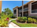 Charming condo building featuring lush landscaping, screened balconies, and a well-maintained walkway under a clear blue sky at 5251 Mahogany Run Ave # 521, Sarasota, FL 34241