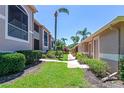 Condo exterior showcasing a well-manicured lawn, mature landscaping, palm trees, and inviting walkways under a clear blue sky at 5251 Mahogany Run Ave # 521, Sarasota, FL 34241