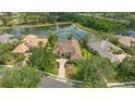 Aerial view of home with tile roof, beautiful landscaping, and surrounded by lush greenery and a serene pond view at 7305 Chatsworth Ct, University Park, FL 34201