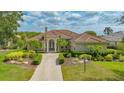 Charming single-story home featuring a tile roof, an arched doorway with columns, and beautifully landscaped front yard at 7305 Chatsworth Ct, University Park, FL 34201