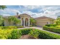 Beautiful home featuring lush landscaping, arched columns, and tile roof providing elegance and curb appeal at 7305 Chatsworth Ct, University Park, FL 34201