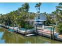 Aerial view of a charming stilt house on a canal with a pool and dock at 750 Tarawitt Dr, Longboat Key, FL 34228