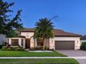 Elegant home featuring a tile roof, well-manicured lawn, tropical landscaping, and a two-car garage at 7864 Grande Shores Dr, Sarasota, FL 34240
