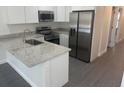 Modern kitchen with stainless steel appliances, white cabinets, and granite countertops at 8810 N Mulberry St, Tampa, FL 33604
