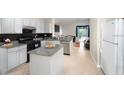 Open kitchen with granite countertops, white cabinets, stainless steel appliances, and an eat-in island at 11274 Beebalm Cir, Lakewood Ranch, FL 34202