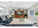 Bright living room with vaulted ceilings, neutral walls, tile flooring, and large entertainment center at 11895 Claremont Dr, Port Charlotte, FL 33981
