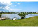 Scenic waterfront view with private dock, lush green lawn, and calm lake reflecting a sunny sky at 11895 Claremont Dr, Port Charlotte, FL 33981