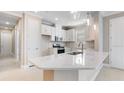 Modern kitchen featuring white cabinets, stainless steel appliances, and a large quartz countertop island at 16202 Isola Pl, Bradenton, FL 34211