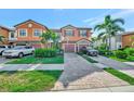 Charming two-story townhome with an attached garage, lush landscaping, and a brick paver driveway at 20228 Lagente Cir, Venice, FL 34293