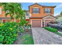 Beautiful two-story townhome featuring a stone accent, attached garage, and colorful, well-maintained landscaping at 20228 Lagente Cir, Venice, FL 34293