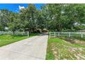 Gorgeous home featuring beautiful mature trees, a long concrete driveway, and a white fence at 2611 221St E St, Bradenton, FL 34211