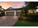 Lovely single-Gathering home featuring a two-car garage and a brick paver driveway surrounded by beautiful landscaping at 3512 Scrub Creek Run, Lakewood Ranch, FL 34211