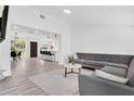 Bright and spacious living room with modern gray sectional sofa, light wood flooring, and open concept design at 3856 Monica Pkwy, Sarasota, FL 34235