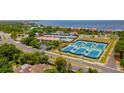 Aerial view of waterfront property with tennis courts and blue paddle ball courts nestled in lush greenery at 4510 El Conquistador Pkwy # 105, Bradenton, FL 34210