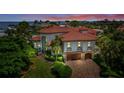 Gorgeous waterfront home boasting lush landscaping and a terracotta tile roof at sunset at 524 Schooner Ln, Longboat Key, FL 34228