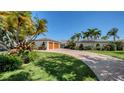 Lovely home exterior featuring a circular brick driveway, lush landscaping, mature trees, and a three-car garage at 642 S Owl Dr, Sarasota, FL 34236