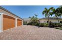 Charming home exterior with unique brick driveway, lush landscaping, and a spacious three-car garage at 642 S Owl Dr, Sarasota, FL 34236