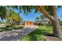 Beautiful home exterior with brick driveway, lush landscaping, mature trees, and a three-car garage at 642 S Owl Dr, Sarasota, FL 34236