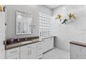 Modern bathroom featuring white cabinets, stylish countertop, glass block window and decorative floral arrangement at 6532 Copper Ridge Trl, Bradenton, FL 34201