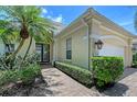 Exterior elevation of a home featuring a brick walkway, stucco, mature landscaping, and a charming entrance at 7528 Ascot Ct, University Park, FL 34201