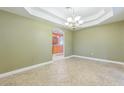 Elegant dining room with tray ceilings, chandelier, and neutral tile flooring, adjacent to the kitchen at 1330 16Th St, Sarasota, FL 34236
