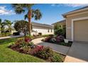 Beautiful front yard with lush landscaping, vibrant flowers, palm trees, and a well-maintained walkway leading to the entrance at 1618 White Breeze Cv, Bradenton, FL 34208